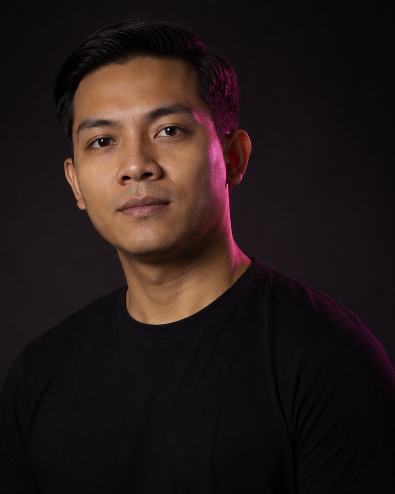 Lelaki Melayu sekitar dua puluh lapan tahun, baju hitam polos, cahaya magenta di tepi wajah